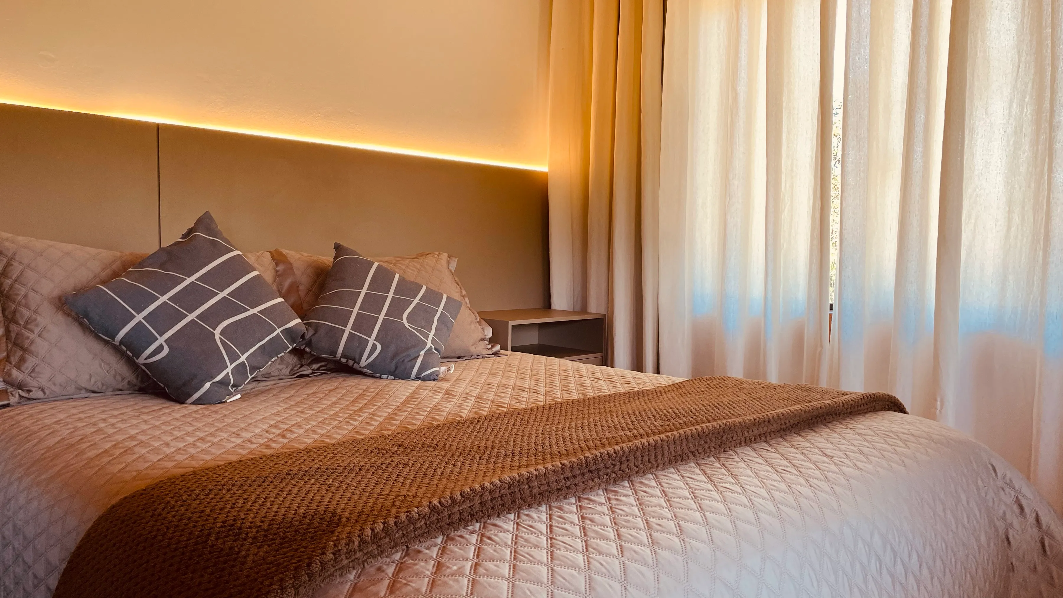 Quarto da cabana com almofadas e roupa de cama em tons de bege
