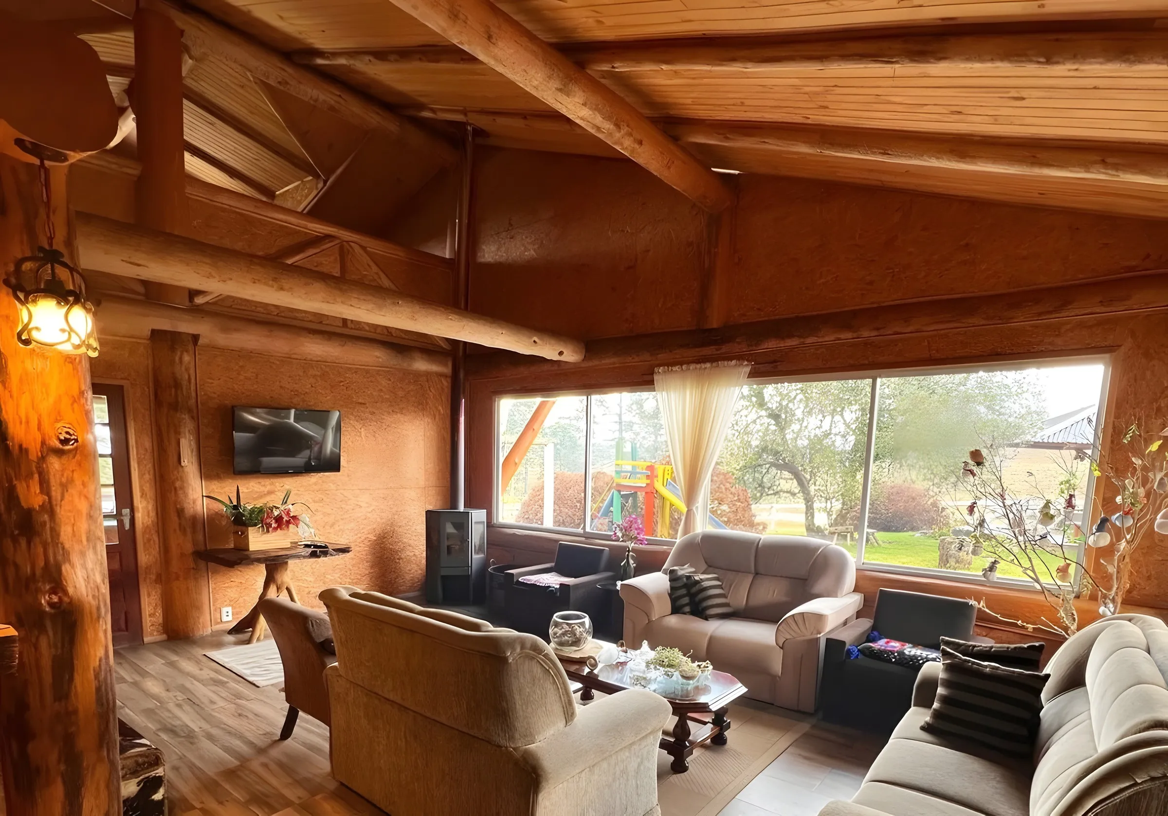 Sala de estar com sofás, teto de madeira e janelas amplas